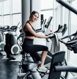 attractive-smiling-girl-onn-exercise-bike-modern-spacious-gym